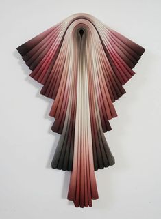 an abstract sculpture made out of folded papers on a wall with white walls in the background