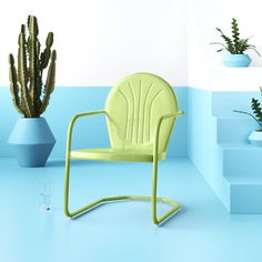 a green chair sitting next to a cactus in a blue room with stairs and potted plants