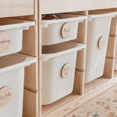 several white plastic bins with wooden labels on them are lined up next to each other