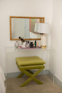 a vanity with a stool and mirror in the corner, along with other makeup products