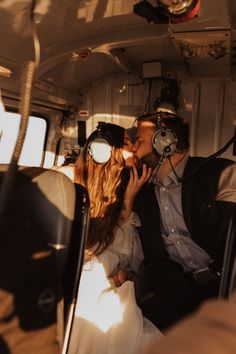 a man and woman are kissing in the back of a small plane with headphones on