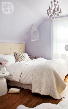 a bedroom with pink walls, white bedding and beige pillows on the headboard