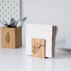 two napkin holders with spoons and utensils in them sitting on a table