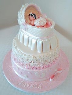 a baby in a cradle on top of a pink and white cake