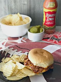 a plate topped with a sandwich and chips next to a bowl of guacamole