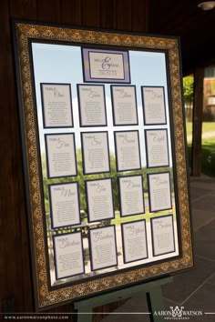 a wedding seating chart is displayed in front of a window at the reception venue for an outdoor ceremony