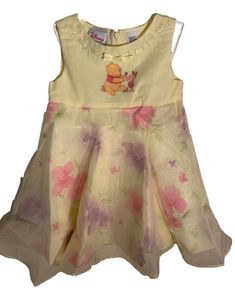 Get ready for Easter or a wedding with this adorable Disney Winnie the Pooh and Piglet yellow dress! The dress features a floral pattern and a round neckline, with a sleeveless fit and flare style that's perfect for the spring and summer seasons. It has a zip closure in the back and falls to knee length or longer, making it great for parties and weddings. This dress is brand new with tags and is a vintage piece from Disney, making it a unique addition to any little girl's wardrobe. It's available in size 2T and is part of the Winnie the Pooh and Disney character family theme. Don't miss out on this cute and stylish dress for your little one! 100% cotton lining 100% polyester overlay New with tag from Disney Store Yellow Easter Dress, Winnie The Pooh Skirt, Spring Sleeveless Disney Dresses, Spring Cotton Minnie Mouse Dress, Disney Infant Clothes, Disney Minnie Mouse Cotton Dresses, Easter Dress, Disney Winnie The Pooh, Girls Wardrobe