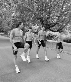 a group of men standing next to each other in the street with no shirts on