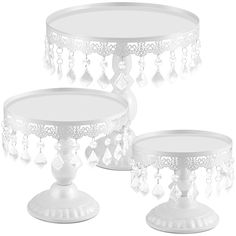 three white cake stands with beaded decorations on them