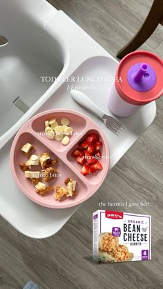 a pink tray with food on top of it next to a bottle of milk and a bowl of strawberries