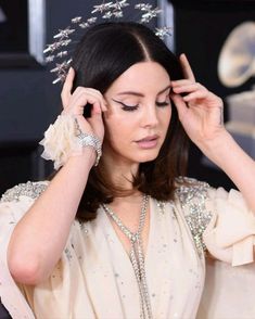 a woman wearing a tiara and holding her hands to her head