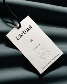 a white business card sitting on top of a black satin material covered table cloth with the word eleuul printed on it