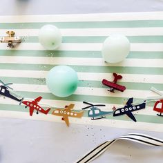 an assortment of toy airplanes and balloons on a striped tablecloth with silverware next to it