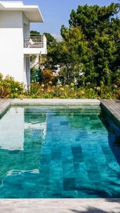 an empty swimming pool in front of a white house