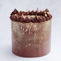 a cake with chocolate frosting and gold sprinkles sitting on a white surface