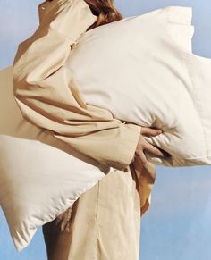 a woman holding two pillows in her hands