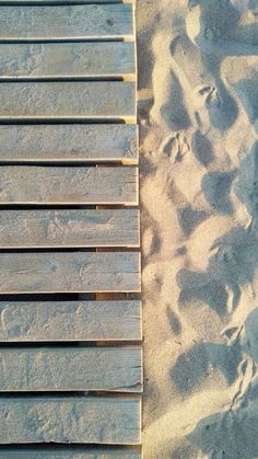 a wooden bench sitting on top of a sandy beach