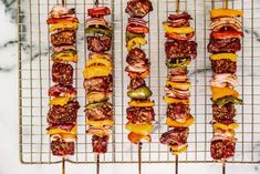 several skewers filled with meat, cheese and vegetables on top of a wire rack