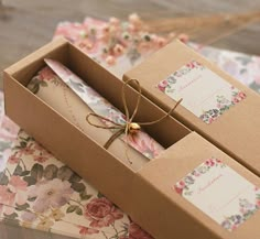 two brown boxes with floral designs on them and tags tied to the top of each box