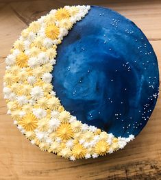 a cake decorated with yellow and white flowers on top of a wooden table next to a knife