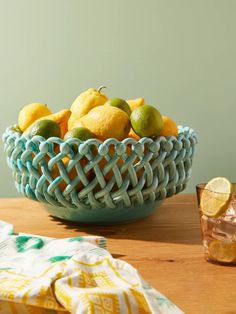 a blue bowl filled with lemons and limes on top of a wooden table