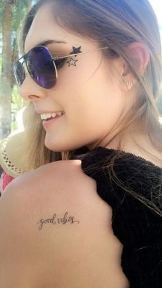 a woman wearing sunglasses has a tattoo on her shoulder