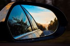 the rear view mirror is reflecting trees in it