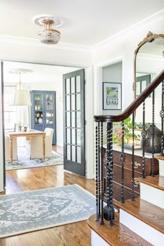 an entryway with stairs, mirror and table in the background on hardwood flooring