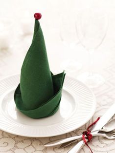 a white plate topped with a green napkin and two silverware holders next to each other