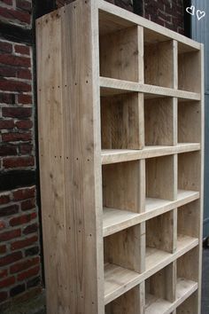 a wooden bookcase sitting next to a brick wall