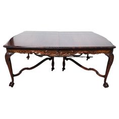 an antique coffee table with carved legs and a wooden top, on a white background