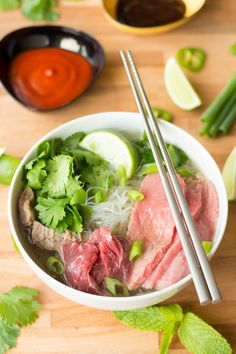 a bowl filled with meat and vegetables next to chopsticks