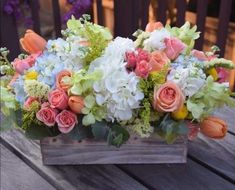 a wooden box filled with lots of different colored flowers