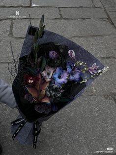 a person holding a bouquet of flowers on the sidewalk in front of a brick building