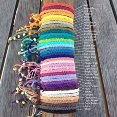 a stack of multicolored crocheted blankets sitting on top of a wooden bench