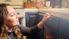 a woman is looking into an oven with the door open and holding a pencil in her hand