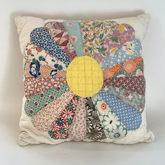 a pillow made out of old quilts with a yellow circle on the front and center