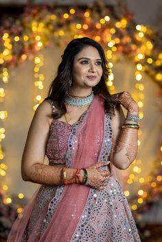 a woman in a pink and silver lehenga with her hands on her hip