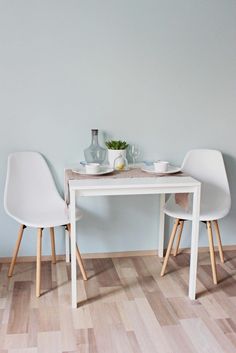 two white chairs sitting at a small table