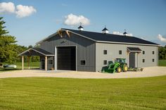 a large gray barn with a tractor parked in front of it on the side of a road