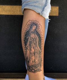 a woman's leg with a tattoo of the virgin mary in black and white