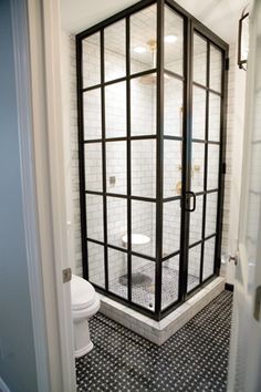 a bathroom with black and white tiled floors, shower stall door open to the toilet