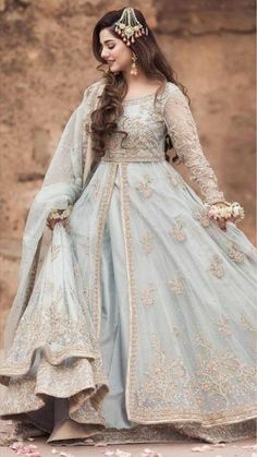 a woman in a blue and white gown with long hair wearing a gold headpiece