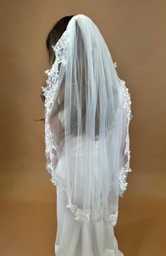 the back of a bride's veil with white lace on it, against a brown background