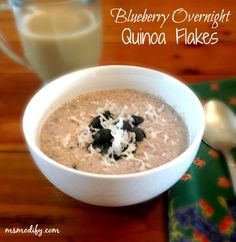 blueberry overnight quinoa flakes in a white bowl next to a glass of milk