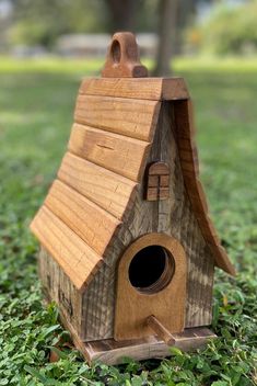 a wooden birdhouse sitting in the grass