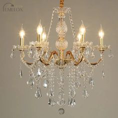 a gold chandelier with crystal drops hanging from it's sides and four lights on each side