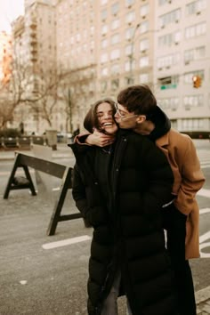 two people standing next to each other in the street with their arms around one another