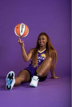 a woman sitting on the ground holding a basketball