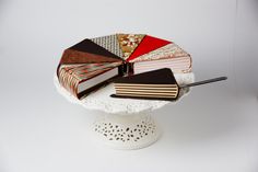 a cake with many different types of books on top of the cake stand, and two forks sticking out of it